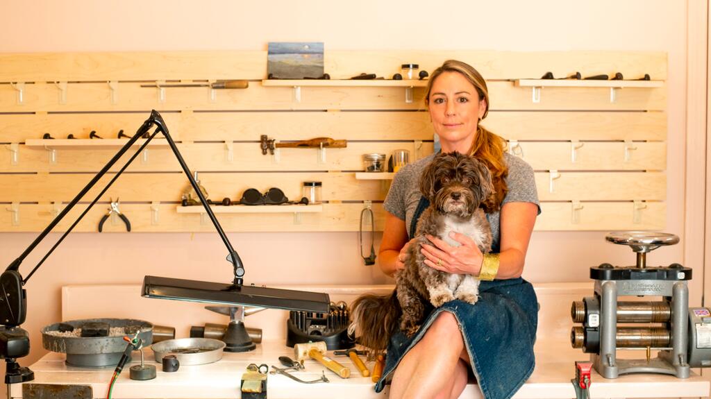 Katey Walker in her workspace with her dog Coco. Photo by Monique Sourinho Katey Walker Laura Putnam Old Saybrook jewelry store