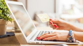 The Better Business Bureau is warning shoppers about a jewelry scam circulating on TikTok. Stock image of hand holding credit card by laptop