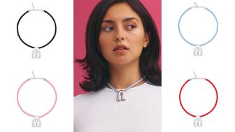 At the center of the “Cloud” necklace is a silver letter on a black, light blue, pink, or red cord ($425). Model wearing Cloud necklace in blue